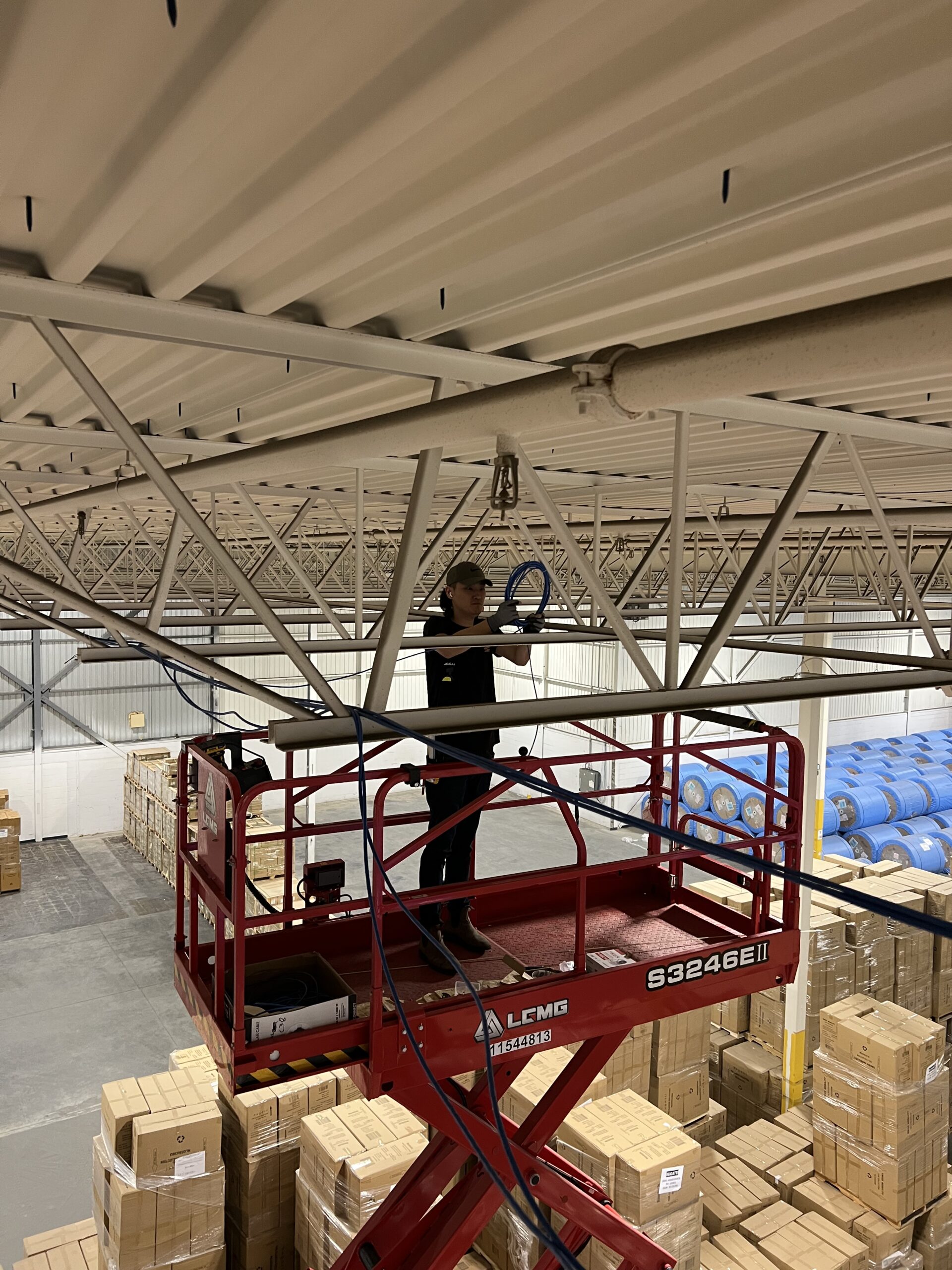 A technician setting up network cables in a warehouse for wi-fi, APs, CCTV , Data Ports, and IDFs